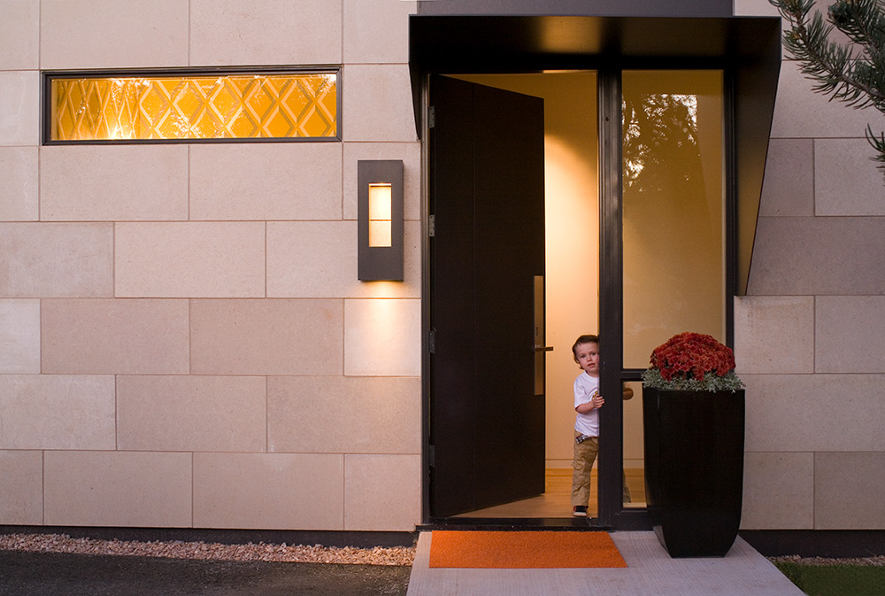 Young boy opening front door to a modern home in Colorado