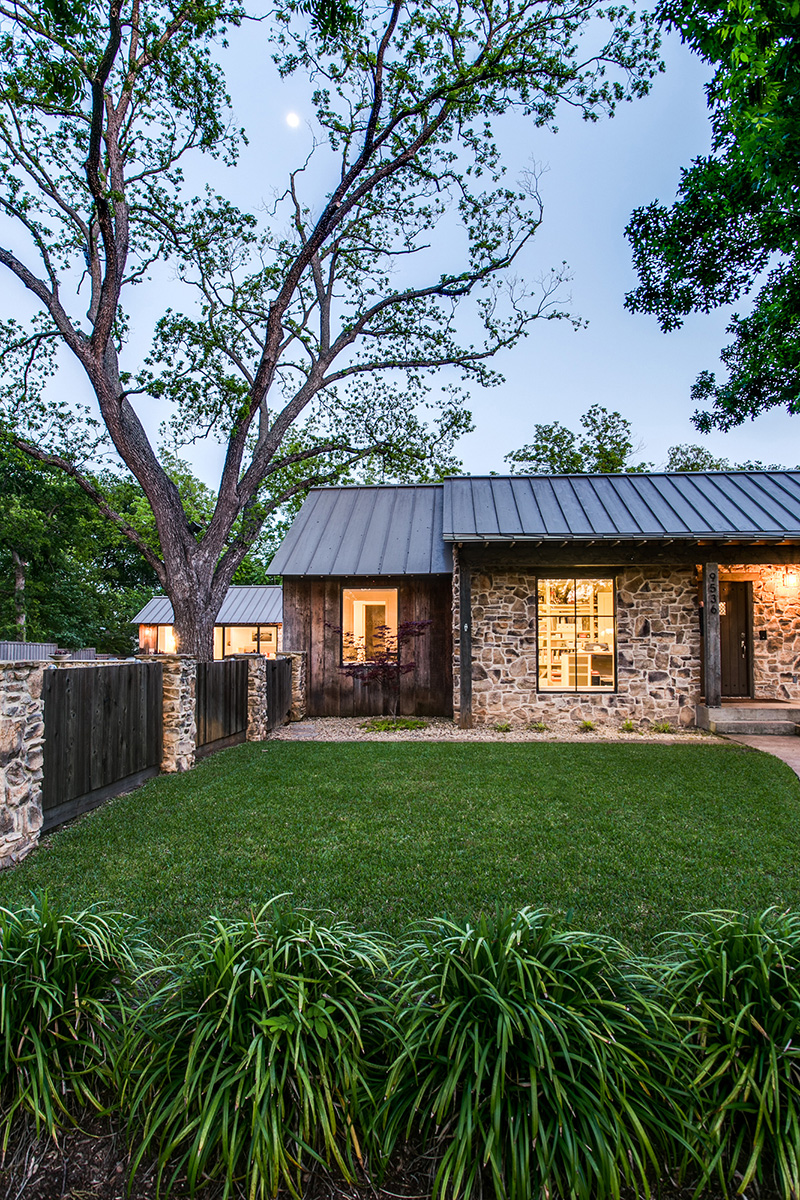 Stone walls and an illuminated interior in the lush garden of a Texas farmhouse
