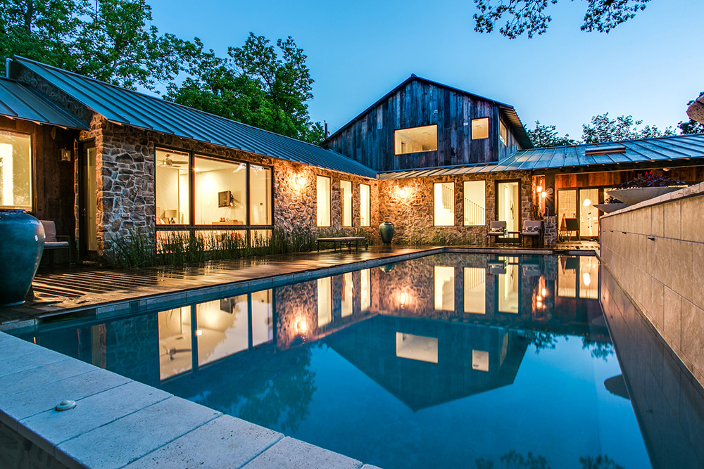 Stone walls and an illuminated interior in the pool area of a Texas farmhouse